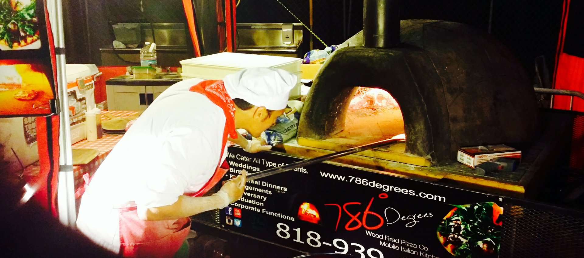 786 degrees pizza chef taking pizza out of the mobile stone wood fire oven at a los angeles catering services event.